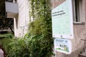 Foto von einem Infoschild mit QR Code und Informationen zum geförderten Gebäudegrün. Im Hintergrund ist auch eine begrünte Fassade zu sehen.