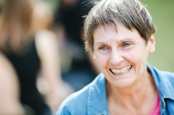 Nahaufnahme einer lachenden Dame mit Kurzhaarschnitt und blauer Jacke