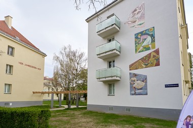 Das Foto zeigt die Hauswand des Vier-Jahreszeiten-Hofs und ein buntes, restauriertes Wand-Mosaik.