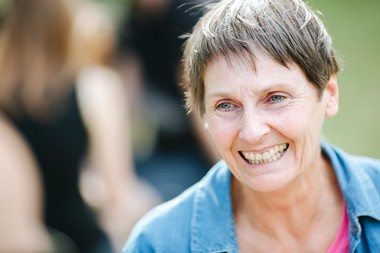 Nahaufnahme einer lachenden Dame mit Kurzhaarschnitt und blauer Jacke