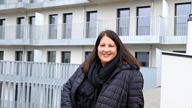 Foto der Wohnbaustadträtin Frau Gaal vor einer weißen Hausfront mit Balkonen