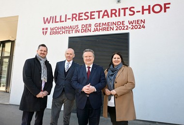 Das Bild zeigt Wohnabustadträtin Kathrin Gaal, den Bürgermeister Michael Ludwig und zwei weitere Personen vor der weißen Hauswand des neuen Willi-Resetarits-Hofes. 