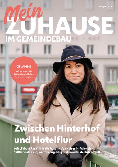 Magazincover „Mein Zuhause im Gemeindebau“ (Frühjahr 2026): Eine Frau mit Hut, Schal und beigem Mantel lehnt an einem Geländer vor einem Wohnhaus; Hinweis auf Gewinne und Titelstory „Zwischen Hinterhof und Hotelflur“.