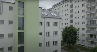 Vorschaubild von dem Video über die Sanierung des Salvador-Allende-Hofs. Es sind zwei Gemeindebauten in weißer und grüner Farbe zu sehen