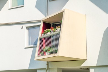 Nahaufnahme von einem überdachten Balkon mit Blumen am Geländer