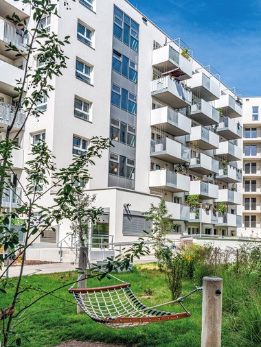 Begrünter Innenhof mit Hängematte im Vordergrund und dahinter Stadtquartier Ödenburgerstraße.