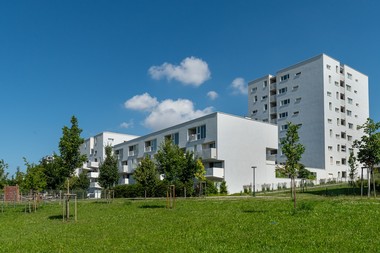 Fernaufnahme des Barbara-Prammer-Hofs. Das Gebäude ist weiß und umgeben von grünen Flächen.