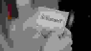 Hand hält eine kleine Karte mit der Aufschrift „Schimmel“ vor unscharfem Hintergrund.