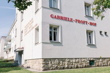 Foto eines Gemeindebaus mit dem sichtbaren Hofnamen "Gabriele-Proft-Hof" an der Fassade