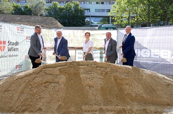Vertreter*innen der Stadt Wien und Wiener Wohnen stehen mit Spaten vor einem Erdhaufen.