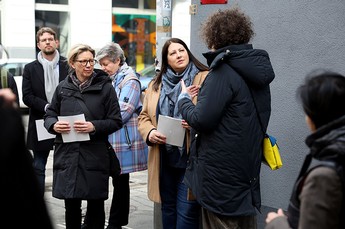 Das Bild zeit Wohnbaustadträtin Katrin Gaal mit anderen Personen beim Zuhören einer Führungsleiterin in einer Straße..