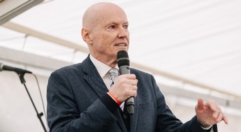 Das Foto zeigt Peter Resetarits im Anzug mit einem Mikrofon bei einer Rede. 