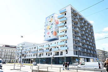 Das Foto zeigt den Willi-Resetarits-Hof mit seiner weißen Fassade, vielen Fenstern und Balkonen. 
