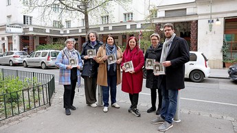 Das Bild zeigt 6 erwachseine Personen, darunter Wohnbaustadträtin Frau Gaal, mit einem Buch in der Hand auf der Straße stehend. 