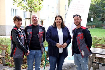 Drei Ordnungsberater*innen und Stadträtin Kathrin Gaál stehen nebeneinander vor einem Gemeindebau und blicken freundlich in die Kamera