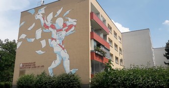 Das Bild zeigt die Wand eines braunen Wiener Gemeindebaus, die mit einem Graffiti verschönert wurde