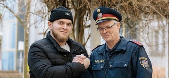 Foto von einem Polizisten und einem jungen Mann mit Mütze, die sich die Hände geben