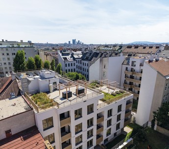 Das Foto zeigt das Flachdach eines weißen Hauses. Auf dem Dach gibt es einen Garten mit Sitzmöglichkeiten.