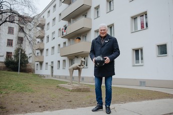Foto von Fußballer Toni Polster vor einem Gemeindebau mit einem Fußball in der Hand