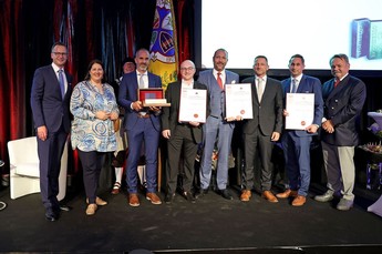 Gruppe and Personen stehen für die Preisverleihung nebeneinander und schauen zur Kamera