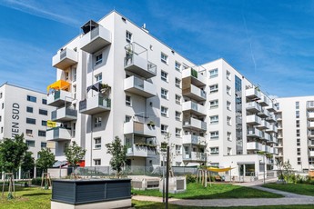 Außenansicht des neuen Stadtquartier Ödenburgerstraße 3B. Das Gebäude hat eine weiße Fassade und einen begrünten Hof