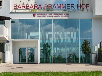 Teilansicht eines Gemeindebaus, auf dem in roter Schrift der Hofname 