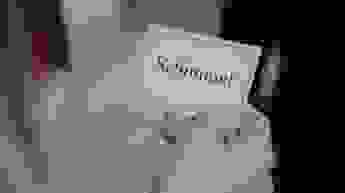 Hand hält eine kleine Karte mit der Aufschrift „Schimmel“ vor unscharfem Hintergrund.