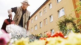 Ein Mann gießt Blumen in einem Gemeindebau-Garten.