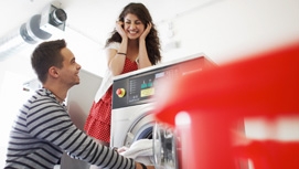 Ein Mann und eine Frau füllen eine Waschmaschine mit Wäsche an.